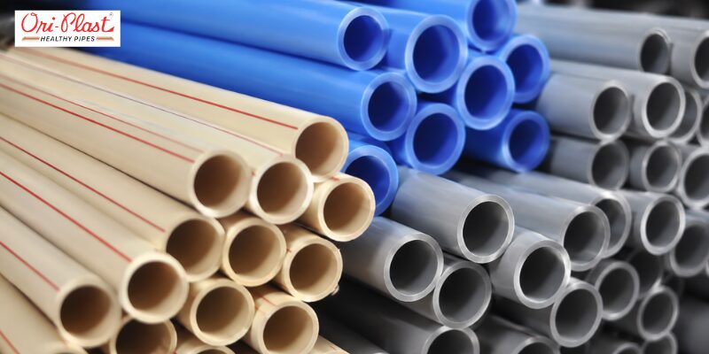 Stacked bundle of beige, blue, and grey plastic pipes with red stripe PVC pipe marking to indicate pipe grade and usage type.